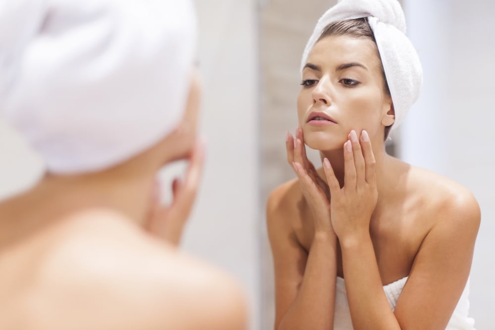Woman moisturizing face using baby oil