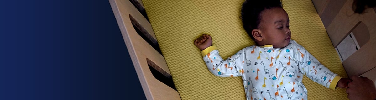A young baby sleeping in his crib