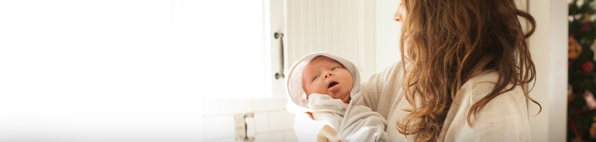 Woman holding her newborn baby wrapped in a towel